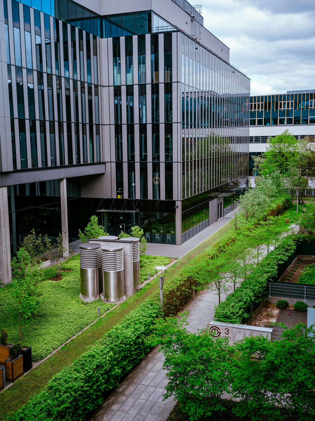 Edificio de oficinas moderno de cristal rodeado de exuberante vegetación.