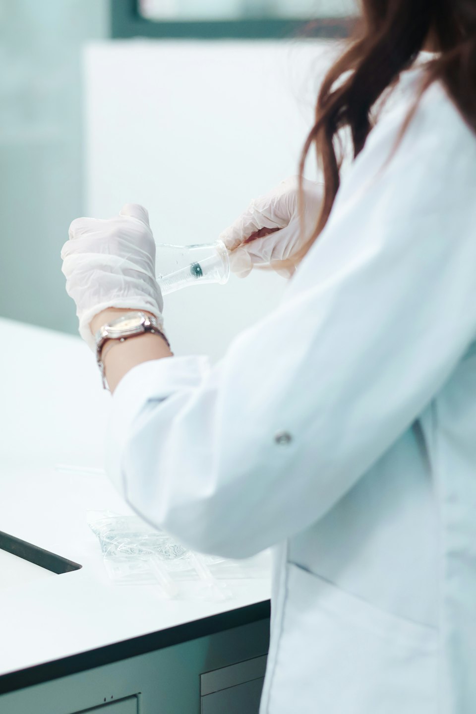 Científico con bata de laboratorio trabajando con vaso de precipitados y jeringa.